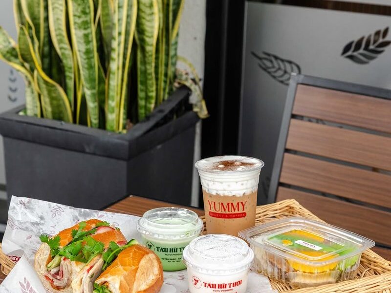 A banh mi sandwich, tofu pudding and dessert jelly on a wicker tray