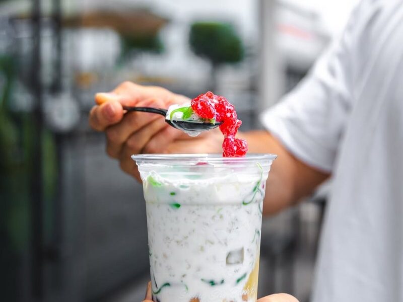 A spoonful of grass jelly and fruit being added to a Suong Sao Banh Lot drink