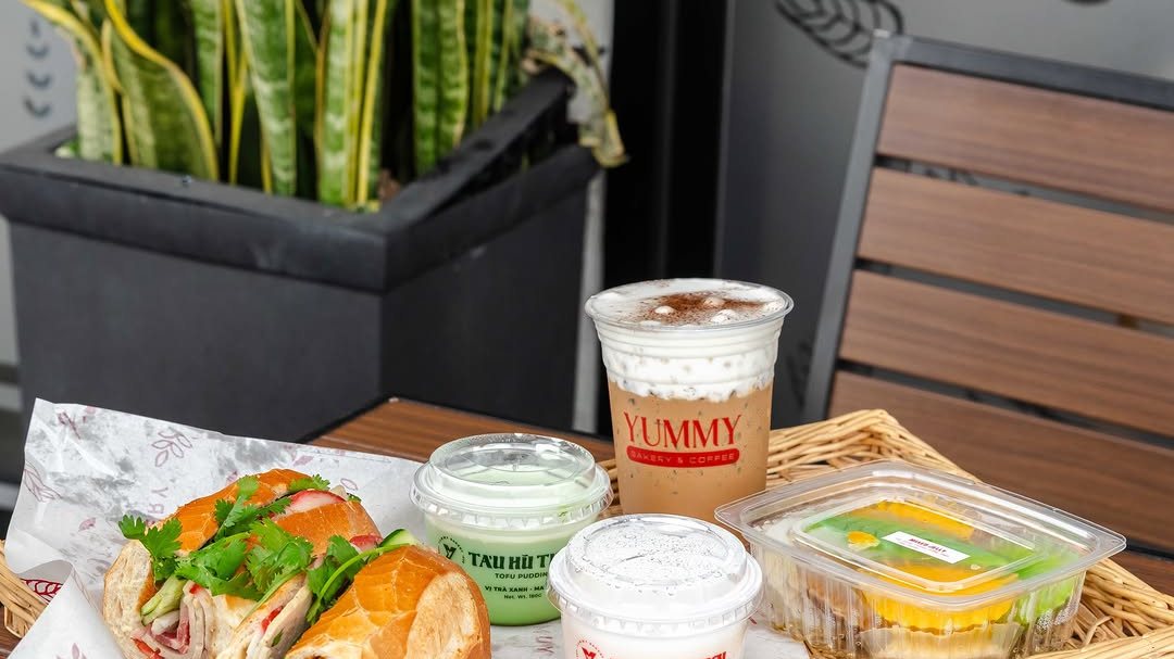 A banh mi sandwich and tofu pudding cups on a wicker tray at Yummy Banh Bao